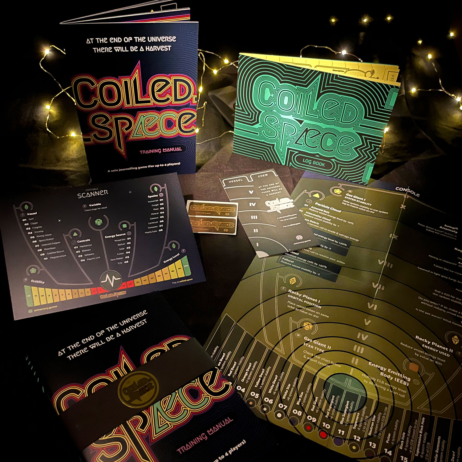 Coiled.Spæce booklet, log book, console poster, scanner postcard, and stickers arranged on a darkened table